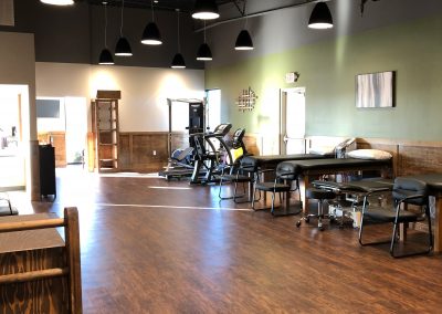 long physical therapy room with adjustment tables and workout equipment