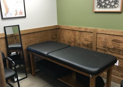 black adjusting table in patient room with green walls