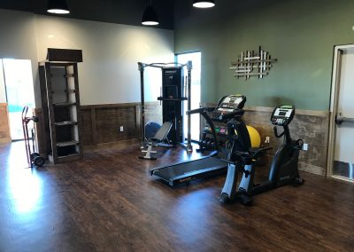 physical therapy room with stationary bike, treadmill and workout equipment